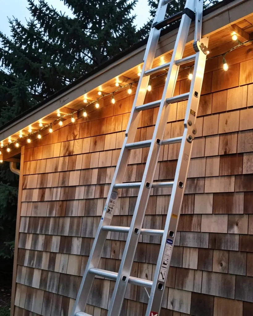 A ladder set against a lit eave